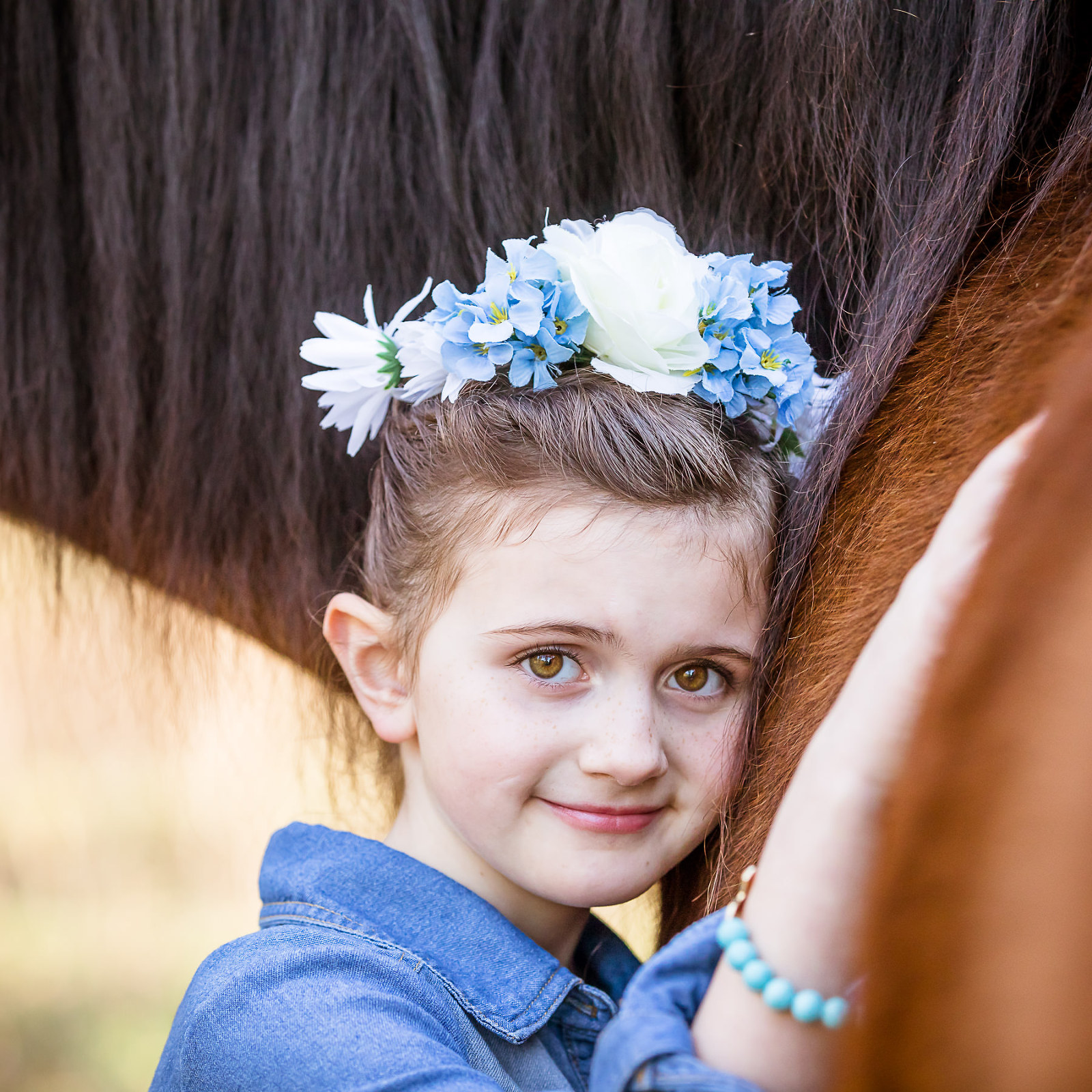 young brown eyed girl hugging horse with blue flowers denim