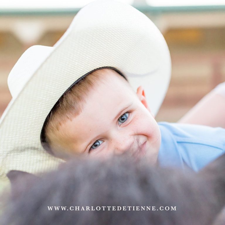little cowboy laying on his mini horse