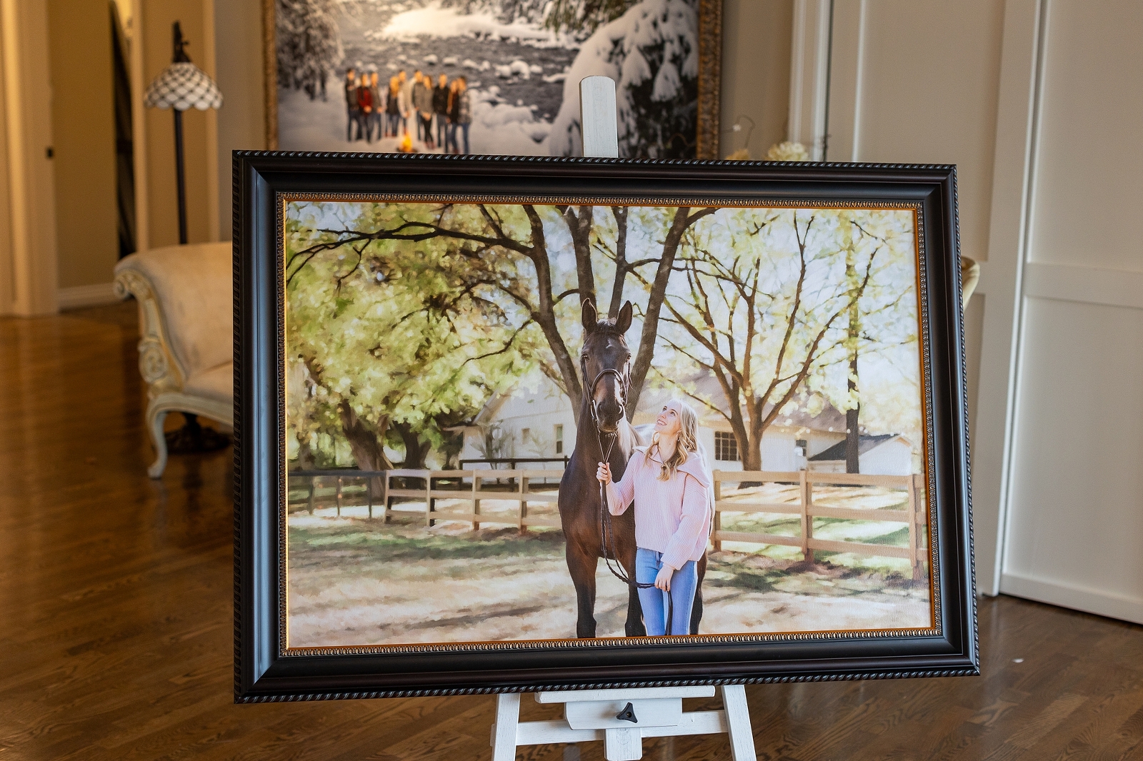 A framed painting of a woman and a horse displayed on an easel in an elegant room.