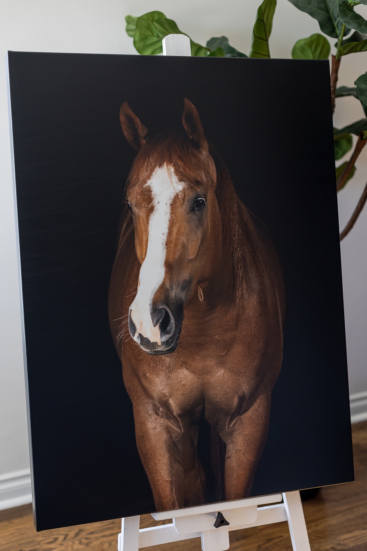 A realistic painting of a brown horse displayed on an easel indoors.