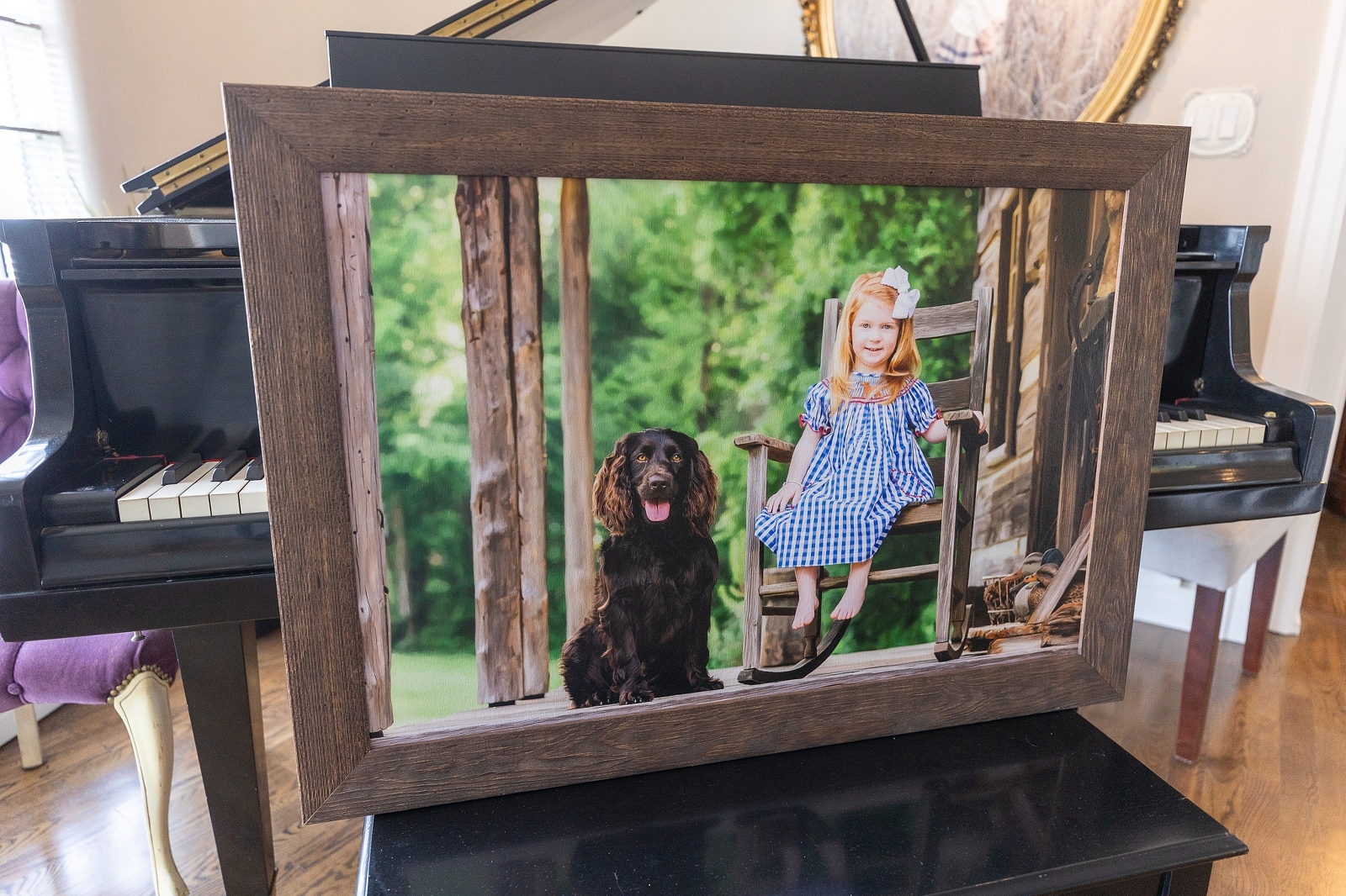 A framed photograph of a smiling young girl and a black dog sitting together, displayed on a piano.