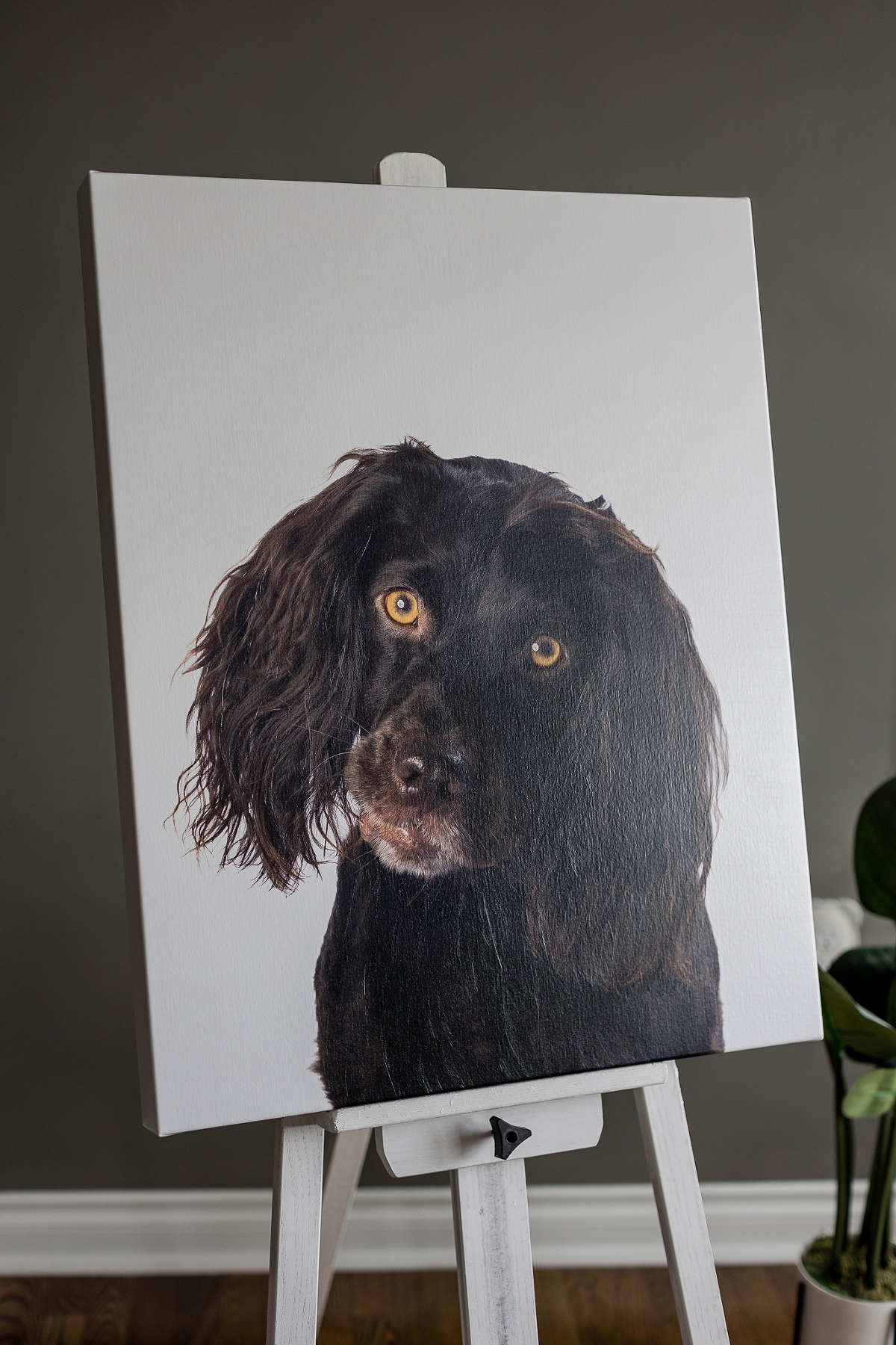 A realistic painting of a black dog displayed on an easel.